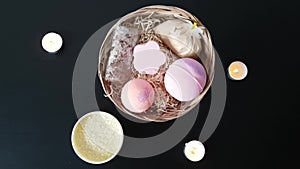 Top view of the set of cosmetics lying on the table. Basket with bath bombs, salt and soap. Burning candle. Romantic atmosphere