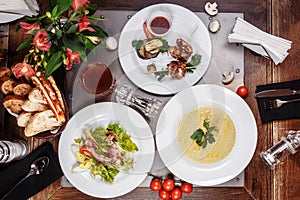 Top view of set food: skewers of mushroom soup, salad and chicken barbecue on a wooden table. three course business lunch