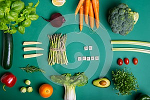 Top view set of healthy raw vegetables and fruits on green background with Go vegan message on wooden blocks. Vegetarian and vegan
