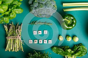 Top view set of healthy raw vegetables on the green background with Eat Green message on wooden blocks. Vegetarian and vegan diet