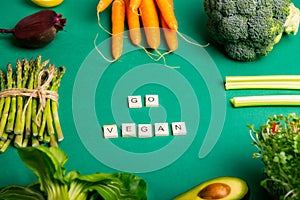 Top view set of healthy raw vegetables on the green background with Eat Green message on wooden blocks. Vegetarian and vegan diet