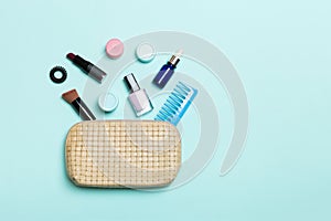 Top view of set of make up and skin care products spilling out of cosmetics bag on blue background. Beauty concept