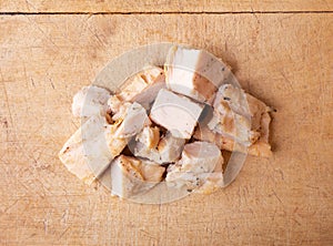 Top view of several pieces of roasted chicken breast on wood cutting board