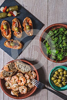 Top view several plates and casseroles with traditional spanish tapas food served on a wooden table