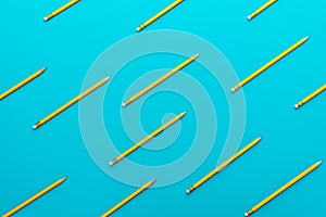 Top view of sharpened simple yellow pencils over turquoise blue background