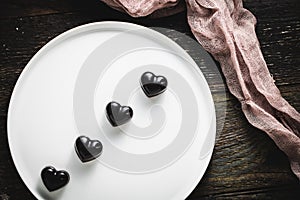 Top view shot of blackheart shaped cholates on the white plate