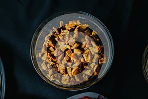 Top view shot of Crispy Pork pieces snacks on glass bwl on black surface