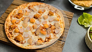 Top view shot of delicious tasty juicy sliced sausage cheesy pizza placed on wooden board around with other fast food crispy fried