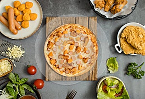 Top view shot of delicious tasty juicy sliced sausage cheesy pizza placed on wooden board around with other fast food crispy fried