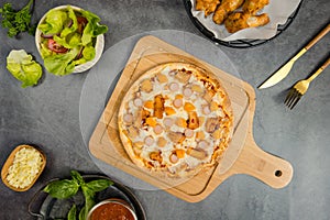 Top view shot of delicious tasty juicy sliced sausage cheesy pizza placed on wooden board around with other fast food crispy fried