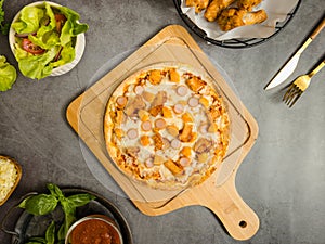 Top view shot of delicious tasty juicy sliced sausage cheesy pizza placed on wooden board around with other fast food crispy fried