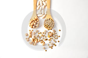 Top view shot of dried lentils, chickpeas, and white beans with wooden spoons on white background