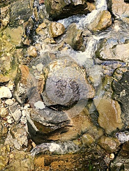 Top view shot of flowing water downstream passing through rocks