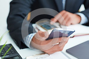 Top view shot of a man`s hands in suit using smart phone in office interior, business man hands using cell phone at