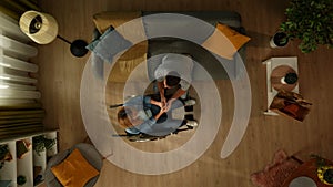 Top view shot of a man sitting on the couch by his partner, a woman with mobility impairment on a wheelchair. They are