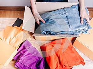 Top view shot of merchandise table with a lot of colorful clothes, jacket jean and boxes for shipping to customers shows modern