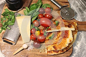 Top view shot of pizza slices with raw ingredients beside it on a wooden board