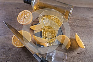 Top view of a shot of whiskey with a knife, slices of orange