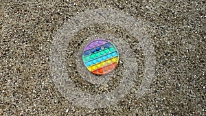 Top view of silicone antistress, pop it fidgets in sand outdoors