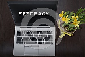 Top view of silver laptop with text feedback and plant on table