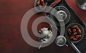 Top view on silver plate with date fruits and coffee cups on the dark red wooden background. Ramadan background. Ramadan kareem