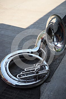 Top view of silver sousaphone bass instrument placed on an outdoor cement floor. photo