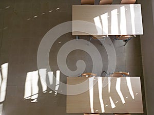 Top view of similar upside down chairs placed on wooden table in light classroom in school after classes