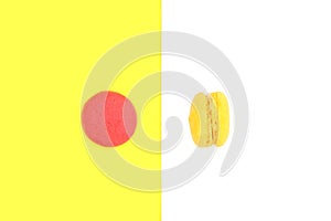 Top view of single red macaron isolated on yellow background and side view of yellow macaron on white background
