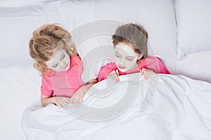 top view of sisters with skincare facial masks lying photo