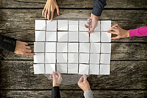 Top view of six hands, male and female, assembling a collage of