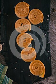 Top view on six rolls from smoked cheese on dark wooden board