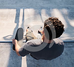 Top view of skater, man and skateboard in city, street or outdoors. Skateboarding, sports and male sitting on ramp