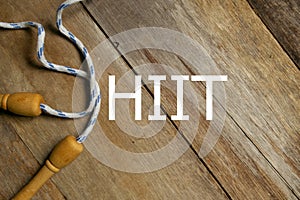 Top view of skipping rope on wooden background written with HIIT. Fitness, healthy and active lifestyles concept