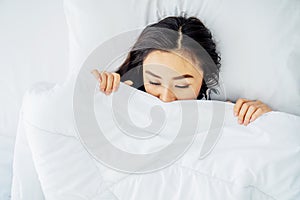 Top view of sleeping asian woman cover face with blanket flat lay. Close-up of young women, sleeping under white blanket