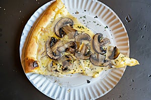 Top view of a slice of pizza with mushrooms on a paper plate. AI generated.
