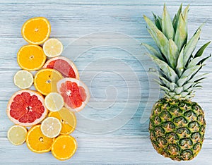 top view of sliced citrus fruits as orange lemon grapefruit with pineapple on wooden background