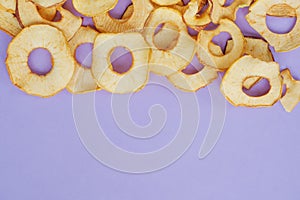 Top view of sliced dry healthy snack apple on violet background. Health lifestyle food. Homemade sweets and dessert. Organic food