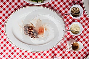 Top view of Sliced medium rare charcoal grilled wagyu Ribeye steak in white plate on red and white pattern tablecloth.