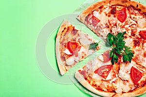 Top view with a sliced pizza on green background.