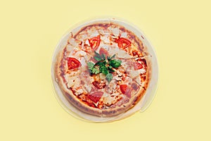 Top view with a sliced pizza on yellow background.