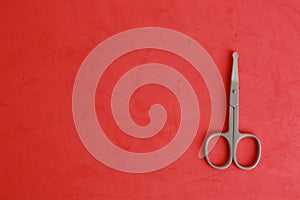 Top view of small baby nail scissors on a red background