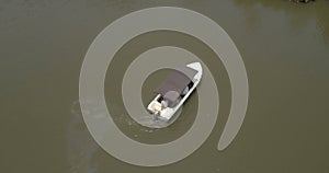 Top view of a small white safari boat turning around in the middle of big beautiful calm green jungle river.