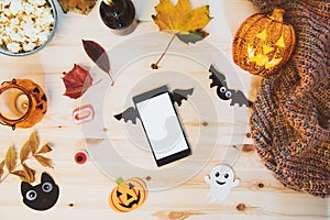 Top view smart phone with blank screen decorated with bat wings and traditional Halloween decor - bats, ghost