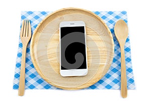 Top view smartphone on wooden dish with spon and fork on white background photo