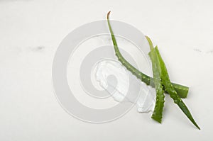 Top view of smear of facial cream adn aloe leaves on the white surface.Empty space photo