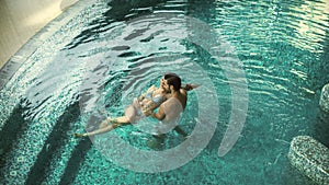 Top view smiling couple swimming in pool. Lovely family resting at whirlpool