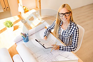 Top view of smiling woman in glasses working on scheme