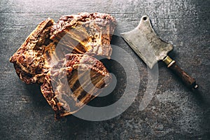 Top view of smoked ribs on a dark metallic surface next to a vintage knife