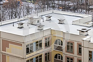 Top view snow flat roof with air conditioners top modern apartment building residential area