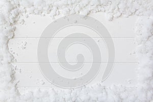 Top view of snow frame on white wooden background with copy space